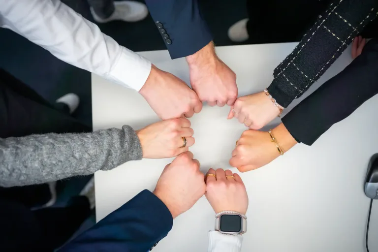 Viele Hände strecken sich als Faust zueinander und bilden einen Kreis, um den Teamgedanken symbolisch darzustellen.
